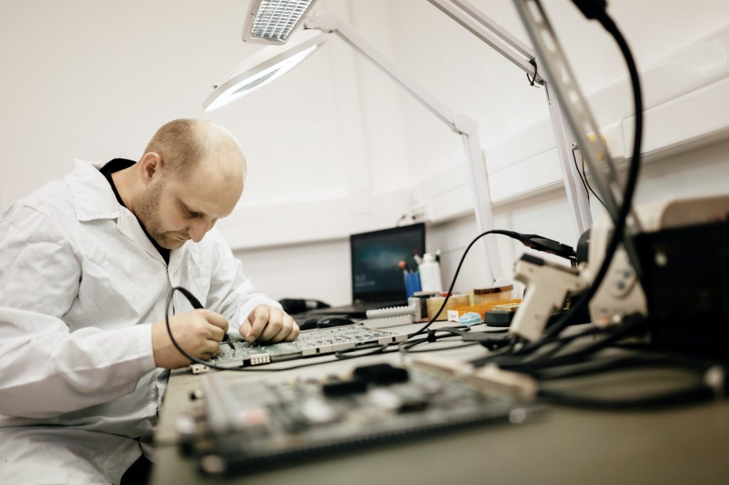 Technician fixing motherboard by soldering
