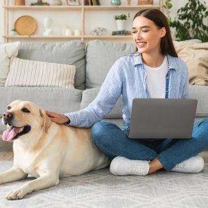 Woman at home with laptop and labrador
